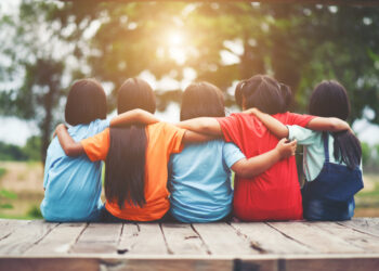 Group of kids friends arm around sitting together