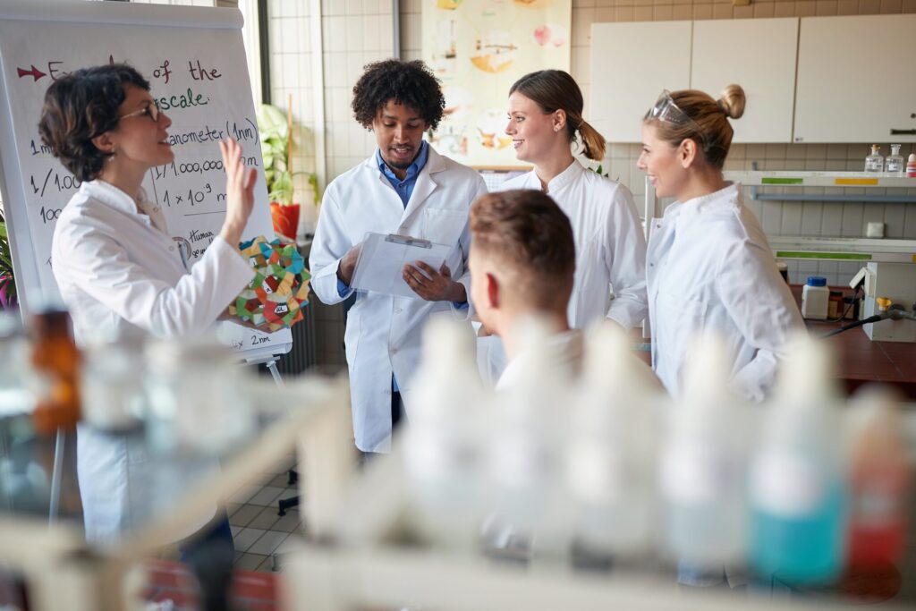 Grupo de investigadores en laboratorio discute resultados y comparte conocimiento, representando el valor de las instituciones científicas independientes para fortalecer la educación y la democracia.