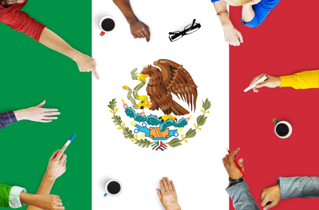 Personas alrededor de la bandera de México trabajando en conjunto, simbolizando la actualización de 200 carreras técnicas y la incorporación de 15 nuevas por la SEP en educación media superior.