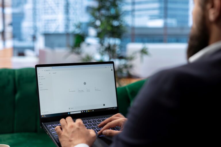 Persona trabajando en una computadora portátil con la interfaz de ChatGPT abierta, enfocada en generar contenido o resolver tareas mediante inteligencia artificial en un entorno de oficina moderna.