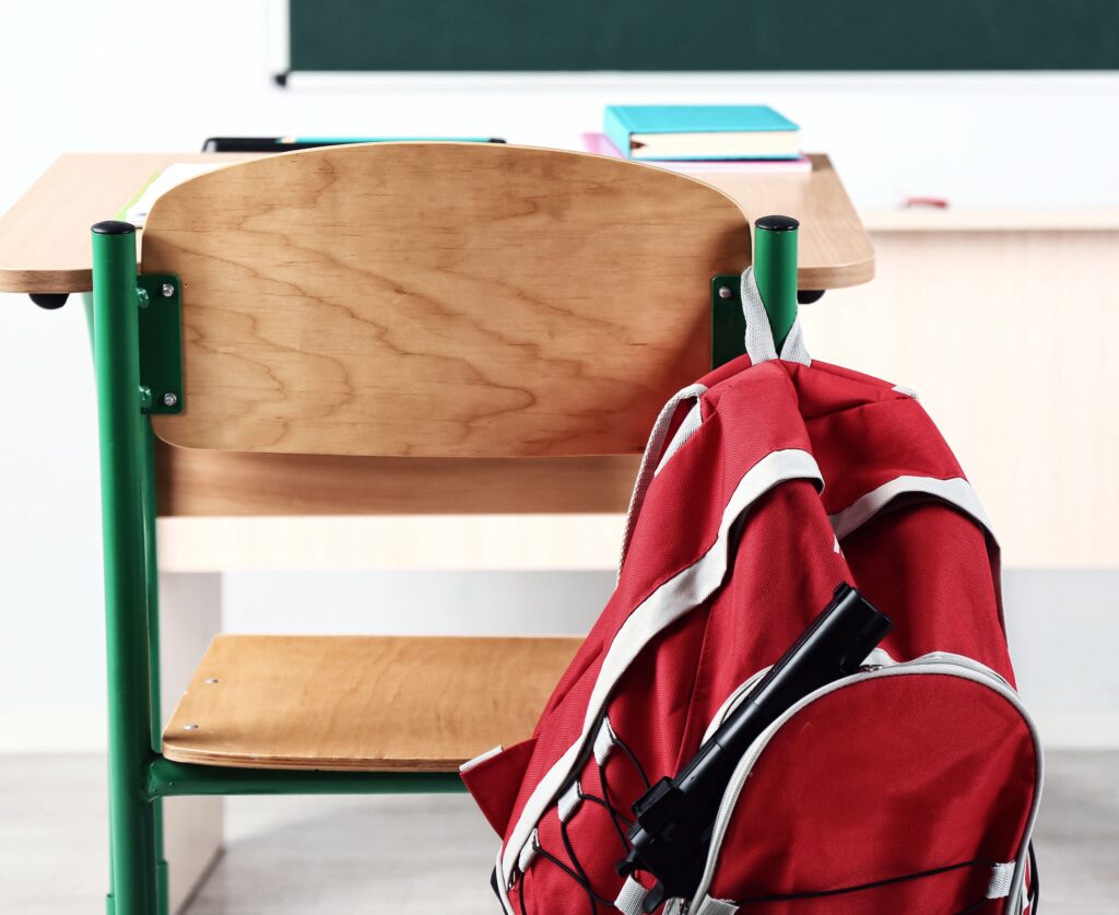 Escritorio escolar vacío con mochila roja en el aula, símbolo de la crisis educativa en América Latina causada por recortes de fondos y falta de inversión.