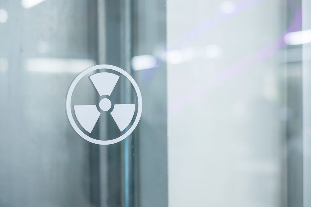 Símbolo de radiación sobre vidrio en entorno industrial, representando protección radiológica y seguridad global.