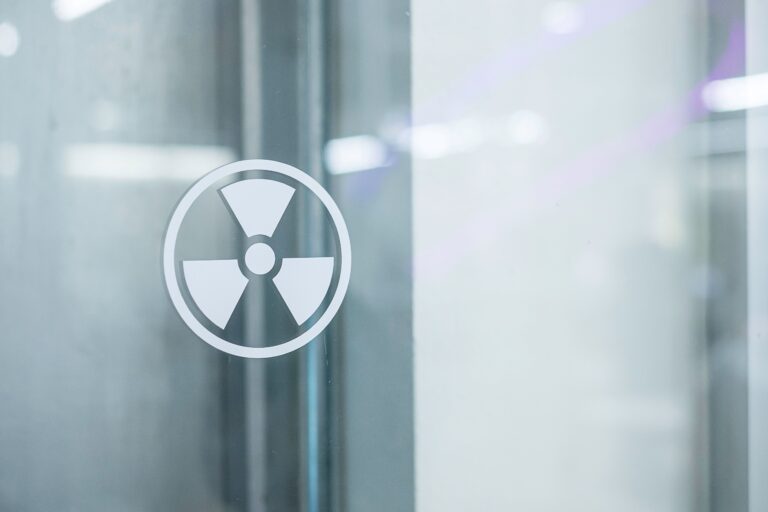 Símbolo de radiación sobre vidrio en entorno industrial, representando protección radiológica y seguridad global.