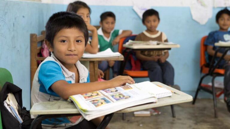 Escuela rural mexicana con estudiantes y maestros, reflejo de la inversión y los desafíos de la educación en México