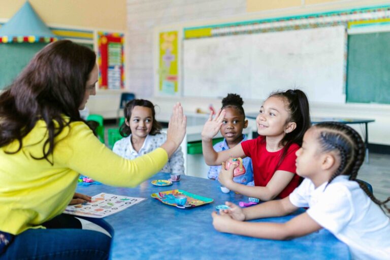 Niños pequeños explorando en el aula, acompañados por docentes atentos y entornos adaptados, en el contexto de la educación infantil