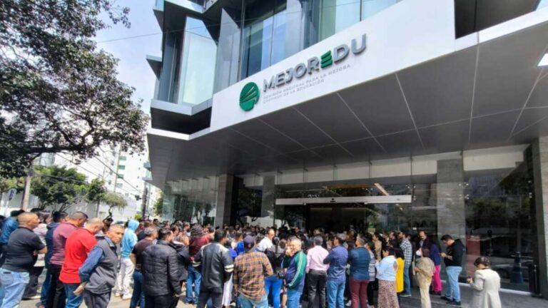 Docentes mexicanos revisando materiales de educación digital en computadoras dentro de una biblioteca moderna