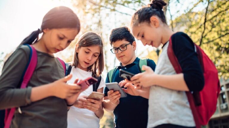 Estudiantes en aula con dispositivos digitales, reflejo del impacto de las pantallas en la educación y el aprendizaje escolar