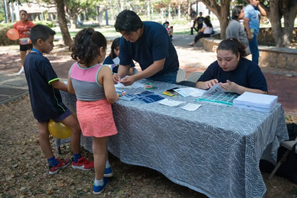 Niñas interactúan con científicos del Club Wal Aerospace en actividades de ciencia para niñas durante una carrera recreativa en Chiapas