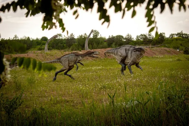 Representación de mamuts y dinosaurios caminando lento, en un paisaje prehistórico argentino con huellas visibles