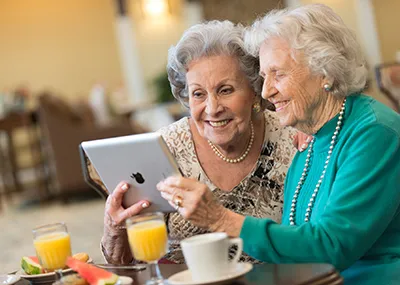 Clase de alfabetización digital para adultos mayores en EE.UU., con instructora enseñando uso de smartphone y conexión social