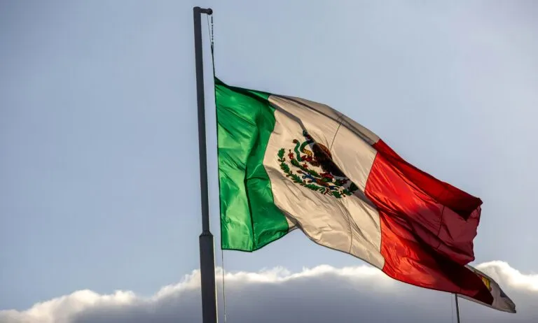 Estudiantes frente a la bandera de México en ceremonia cívica escolar por el Día de la Bandera, símbolo de identidad nacional