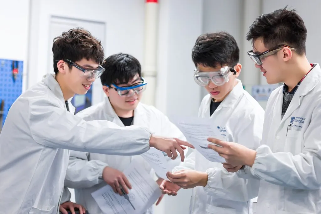 Estudiantes de doctorado en laboratorio universitario en China desarrollan prototipos, reflejando enfoque de educación superior China en innovación aplicada.