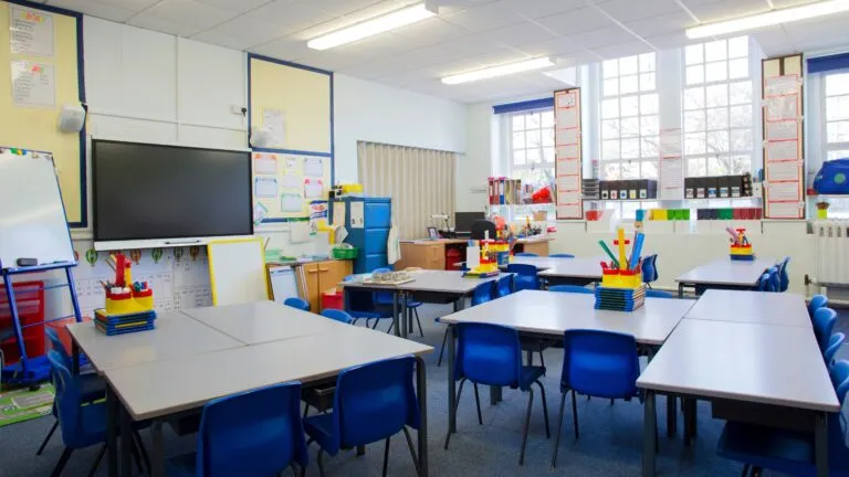 crisis educativa en Inglaterra con aula vacía y estudiantes ausentes reflejando impacto en educación y empleo juvenil