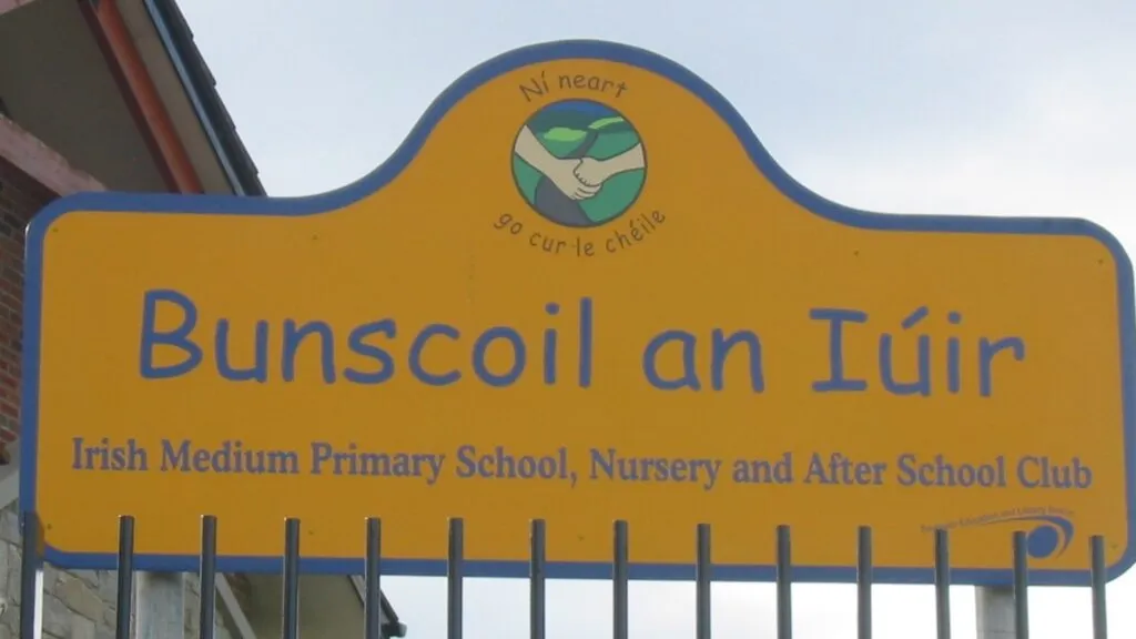 Educación en irlandés reflejada en letrero de escuela primaria bilingüe en Irlanda del Norte con señal visible de enseñanza en idioma irlandés