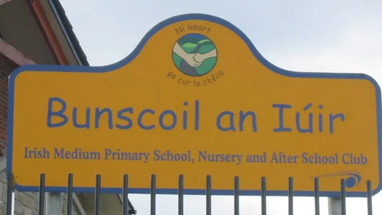 Educación en irlandés reflejada en letrero de escuela primaria bilingüe en Irlanda del Norte con señal visible de enseñanza en idioma irlandés