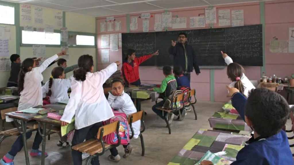 Docentes y estudiantes en aula moderna de Marruecos ante brechas educativas, autonomía docente y retos digitales del sistema escolar