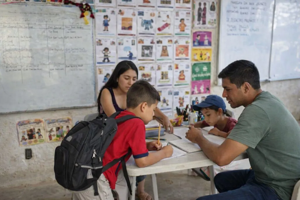 Niñas y niños en movilidad participan en clase del Programa de Educación Migrante en México con materiales escolares y docente al frente