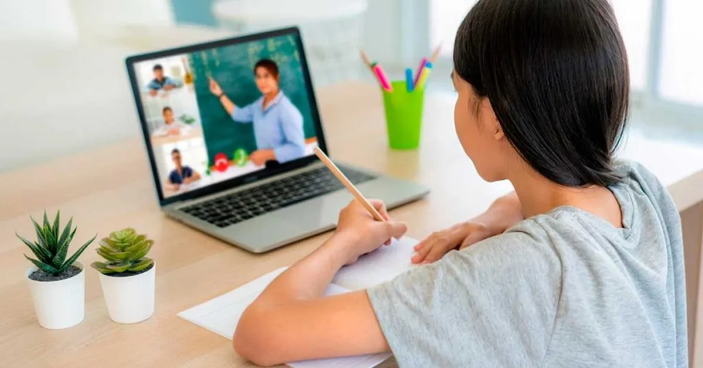Estudiantes y docentes en aula moderna muestran cómo la pandemia y educación escolar impulsaron aprendizaje flexible y colaboración.