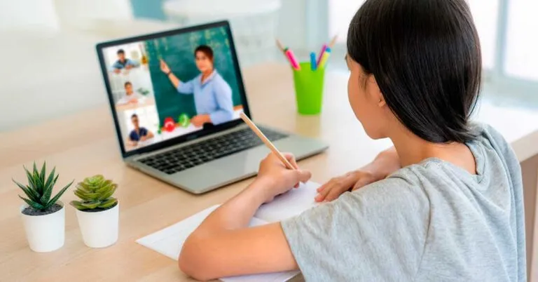 Estudiantes y docentes en aula moderna muestran cómo la pandemia y educación escolar impulsaron aprendizaje flexible y colaboración.